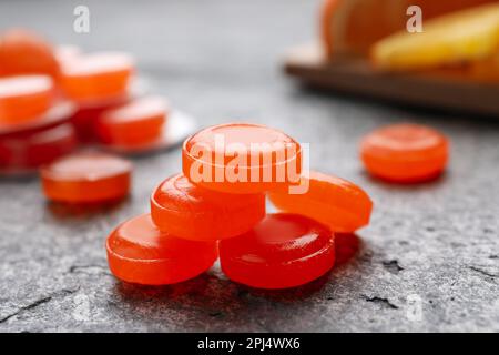 Many orange cough drops on grey table, closeup Stock Photo