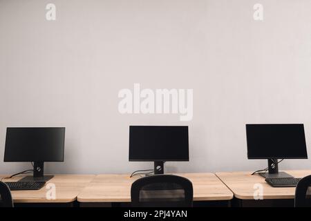 Open office interior. Modern workplaces with computers near light grey wall Stock Photo