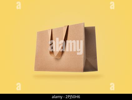 Kraft paper bag on yellow background. Mockup for design Stock Photo