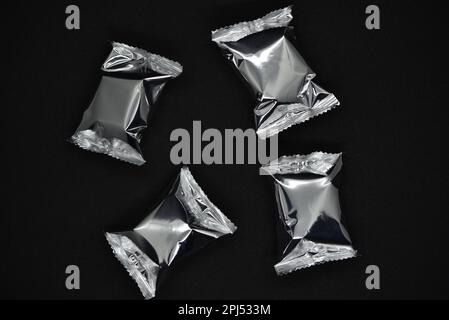 Candy in shiny blisters on a black background. Candy in a shiny package. Stock Photo