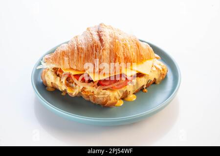 Brioche croissant chicken sandwich on a blue plate white background. Stock Photo