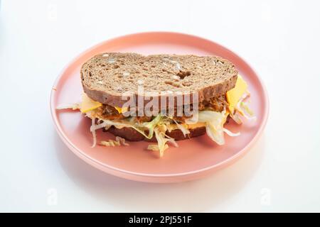 Rye bread pulled beef sandwich on a pink plate white background. Stock Photo