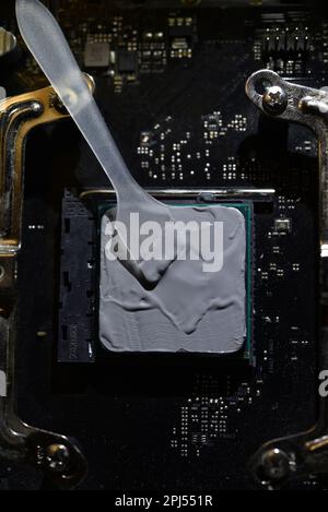 Applying thermal paste to the surface of the computer processor. Thermal interface on the processor. Stock Photo