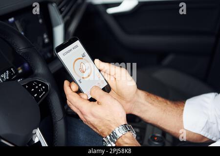 Close up view of man's hand that holds phone with labels and icons. Conception of remote control Stock Photo