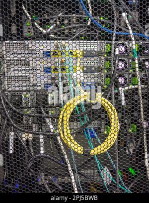 Coiled yellow cable connecting digital equipmnet installed in a rack Stock Photo