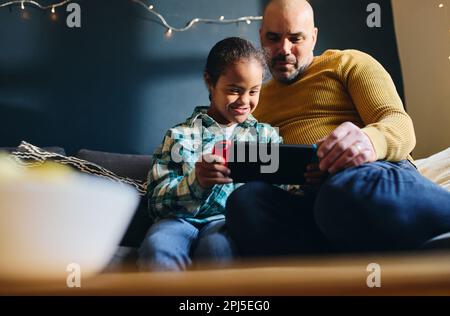 Father supporting son with Down syndrome playing computer game Stock Photo