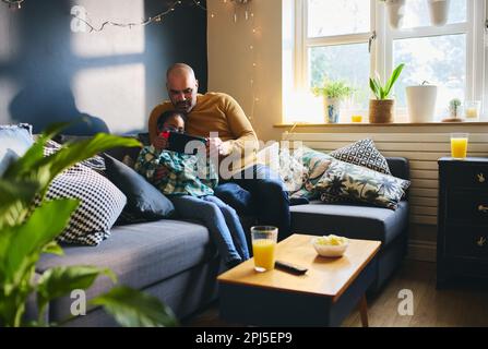 Multiracial father and son with Down syndrome playing computer game Stock Photo