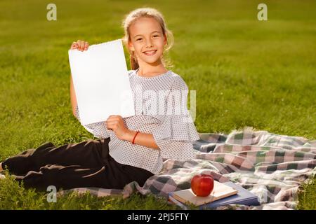 closeup portrait teen girl with banner for your text in hands. woman holding flyer page. invitation to summer school camp Stock Photo