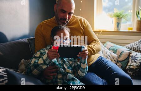 Father watching son with Down syndrome play computer game Stock Photo