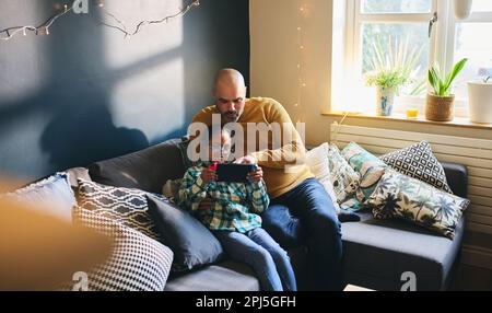 Multiracial father playing computer game with son who has Down syndrome Stock Photo