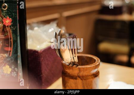 fancy wood cutlery Holder with forks and spoons. on a table in a fancy restaurant with incandescent light. Vintage, retro look. Stock Photo