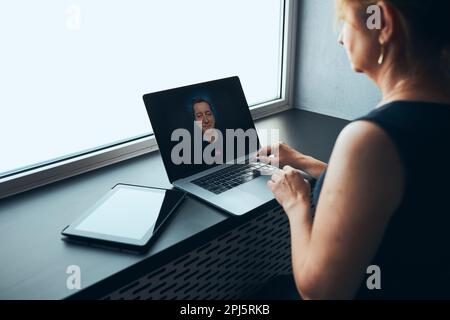 Businesswoman having business video call on laptop in office. Mature busy woman remotely working from office. Female manager using digital devices. Re Stock Photo