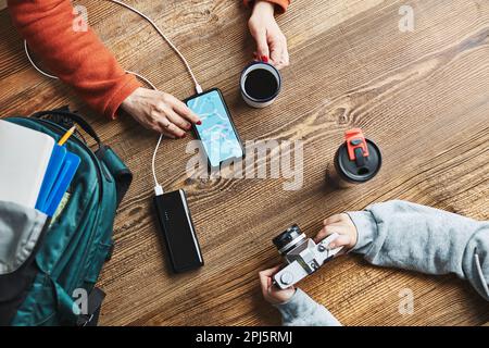 Family planning vacation trip. Woman searching travel destination and routes using navigation map on mobile phone. Girl setting up camera. Charging sm Stock Photo