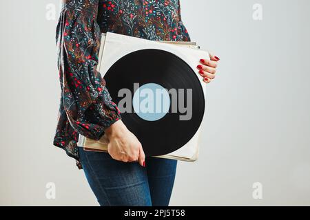 Woman holding vinyl records. Music passion. Listening to music from analog record. Playing music from analog disk on turntable player. Enjoying music Stock Photo