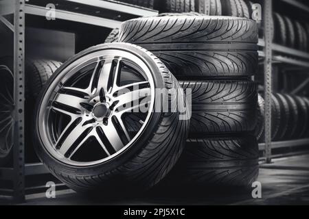 A set of summer wheels in a tire warehouse, against the background of tire racks. Beautiful cool alloy wheels on a black background, seasonal tire Stock Photo