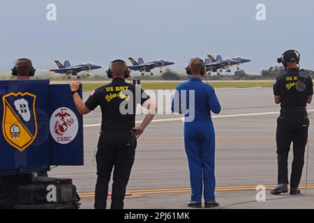 Four of the United States Navy Blue Angels F-18 flight demonstration team jets take off with members of the ground crew in the foreground. Stock Photo