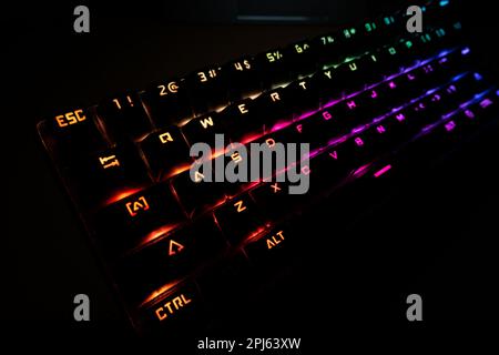 RGB backlit keyboard from left angle inside a dark gaming room at night Stock Photo