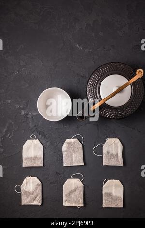 Assorted tea bags with tea pot and cup on black stone background Stock Photo