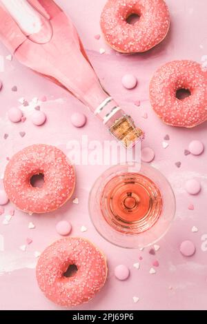 Rose wine or cocktail with pink donuts and pink chocolate beans on pink background Stock Photo