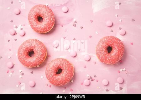 Donuts with pink icing and pink chocolate beans on pink background Stock Photo