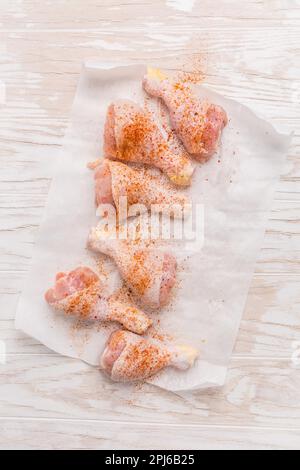 Raw chicken legs with seasoning on wooden kitchen table Stock Photo