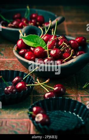 Organic cherries in bowl with baking pan on kitchen table Stock Photo