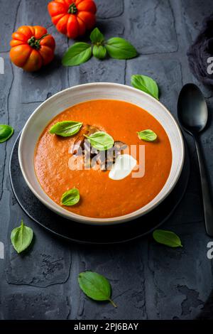 Homemade tomato soup with roasted eggplant and basil on dark background Stock Photo