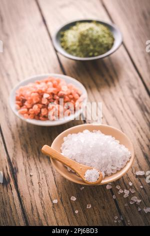 Assortment of salts in bowls : white rock salt, Himalayan salt and chives salt on wooden background Stock Photo