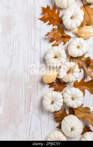 Happy thanksgiving - background with white pumpkins and autumn leaves on white wooden background Stock Photo