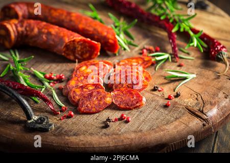Red Spanish chorizo sausage with herbs and spices on wooden cutting board Stock Photo