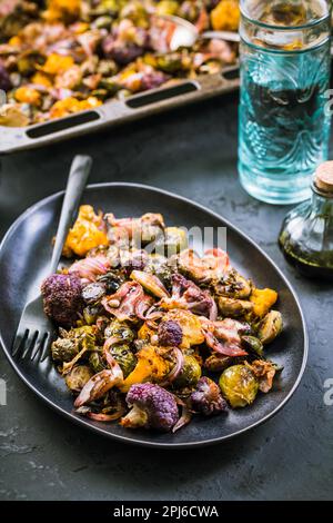 Healthy food - Baked vegetables with Purple Brussels sprouts, broccoli, cauliflower and onions on baking sheet Stock Photo