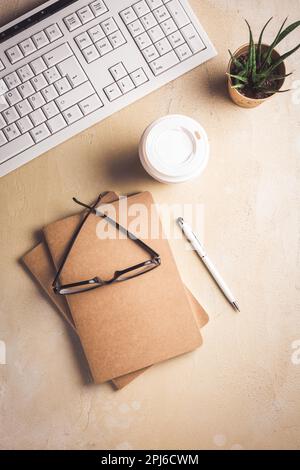 Modern office desk table with laptop computer, notepad, tablet, plant, glasses and pen with cup of coffee Stock Photo