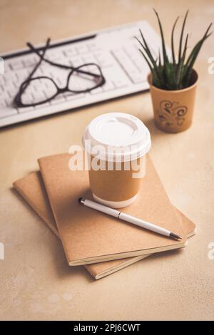 Modern office desk table with laptop computer, notepad, tablet, plant, glasses and pen with cup of coffee Stock Photo