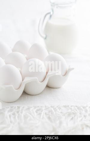 Organic milk and fresh eggs on white kitchen table Stock Photo