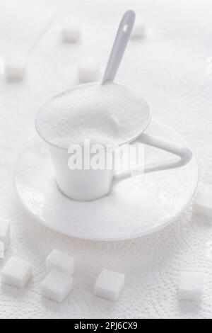 White granulated sugar in white cup with spoon on white background Stock Photo