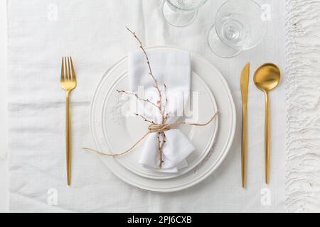 Place setting in white - plates, cutlery in gold, napkin Stock Photo