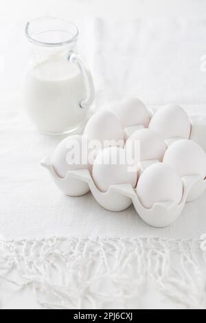 Organic milk and fresh eggs on white kitchen table Stock Photo