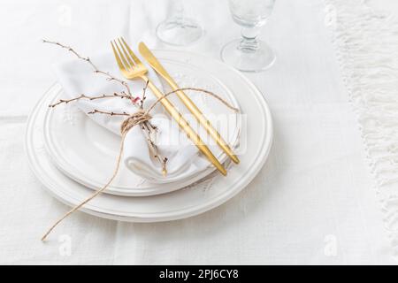 Place setting in white - plates, cutlery in gold, napkin Stock Photo