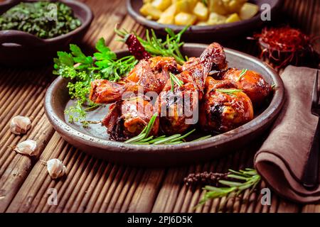 Marinated chicken drumsticks with baked potatoes and spinach on wooden background Stock Photo