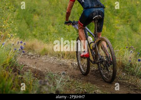 male mountain bike cyclist riding on cross-country cycling, dirty drops on bike and clothes, race in cloudy trail Stock Photo