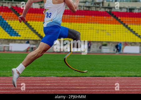 close-up legs athlete runner on prosthesis running stadium track, disabled athlete para athletics competition, summer sports games Stock Photo