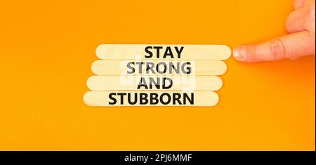 Stay strong and stubborn symbol. Concept words Stay strong and stubborn on wooden stick. Beautiful orange table orange background. Motivational busine Stock Photo