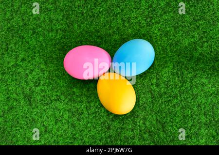 Bright color painted easter eggs on green grass background, flat lay view from above Stock Photo