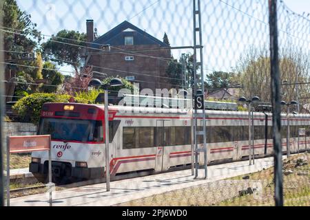 Commuter train of the community of Madrid passing through an open-air station Stock Photo