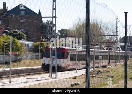 Commuter train of the community of Madrid passing through an open-air station Stock Photo