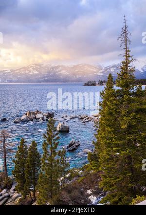 Lake Tahoe captured under dramatic skies with pine forests and snow capped mountains Stock Photo