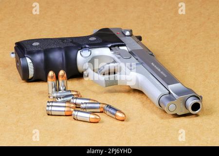 bullet 9mm parabellum and Beretta 92FS, M9 gun on brown paper background. Stock Photo
