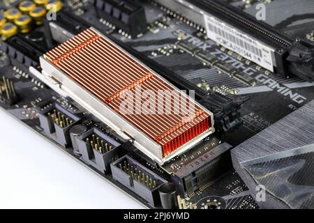 Solid state drives with copper heat sink for computer - ssd sata, NVME PCIe, SATA SSD m key, b key installed on modern computer motherboard. Stock Photo