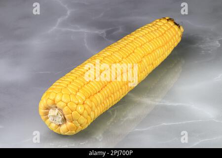 Fresh raw Corncobs or corn ears with green leaves isolated on reflection surface. Stock Photo