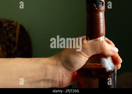 female hand holds a bottle of whiskey in quarantine Stock Photo